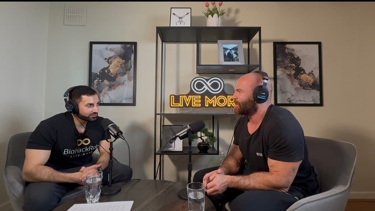 Two men wearing headphones and speaking into microphones for a podcast in a modern studio.