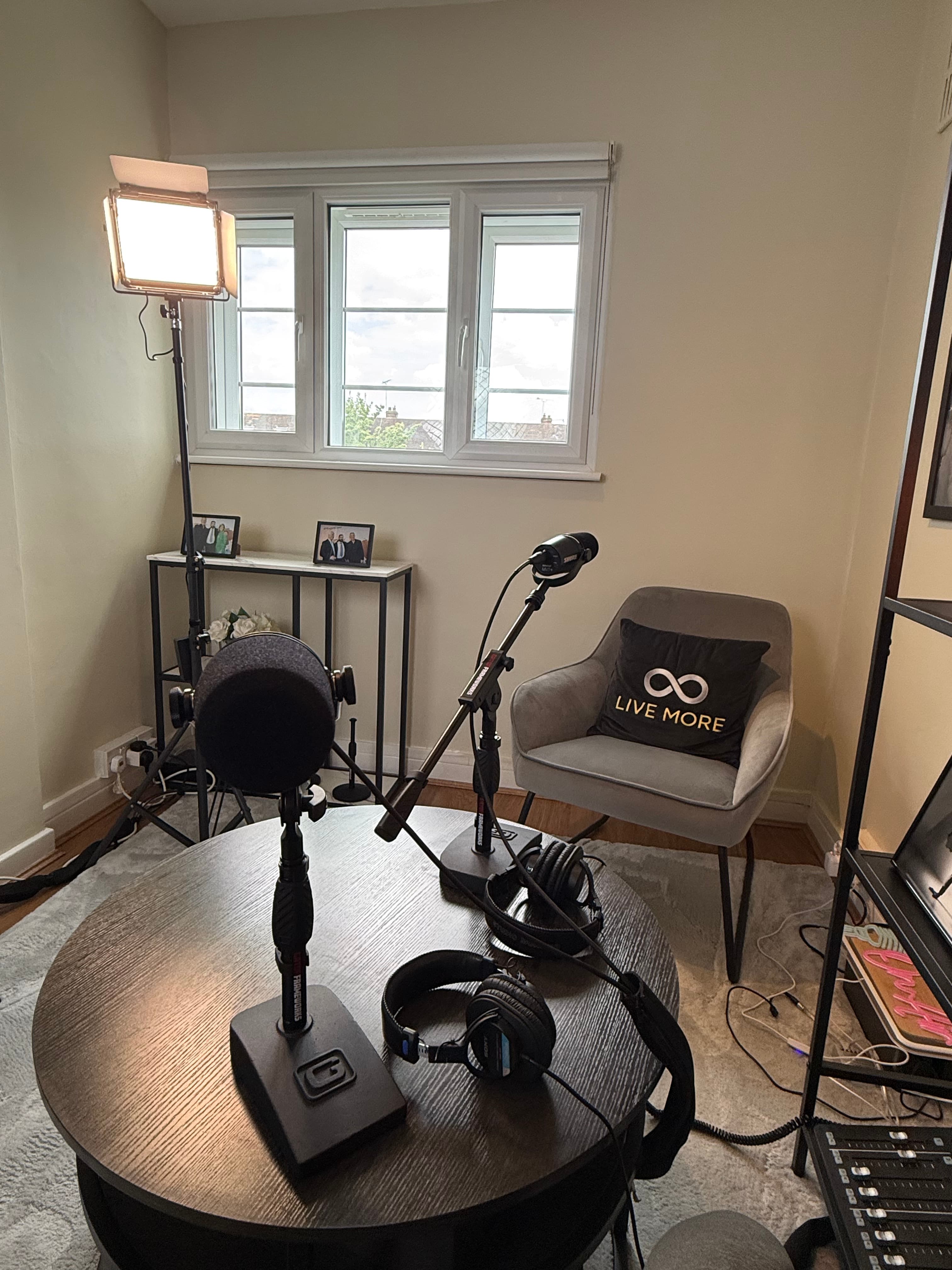 Podcast studio setup with microphones, headphones, a round table, and a bright studio light.