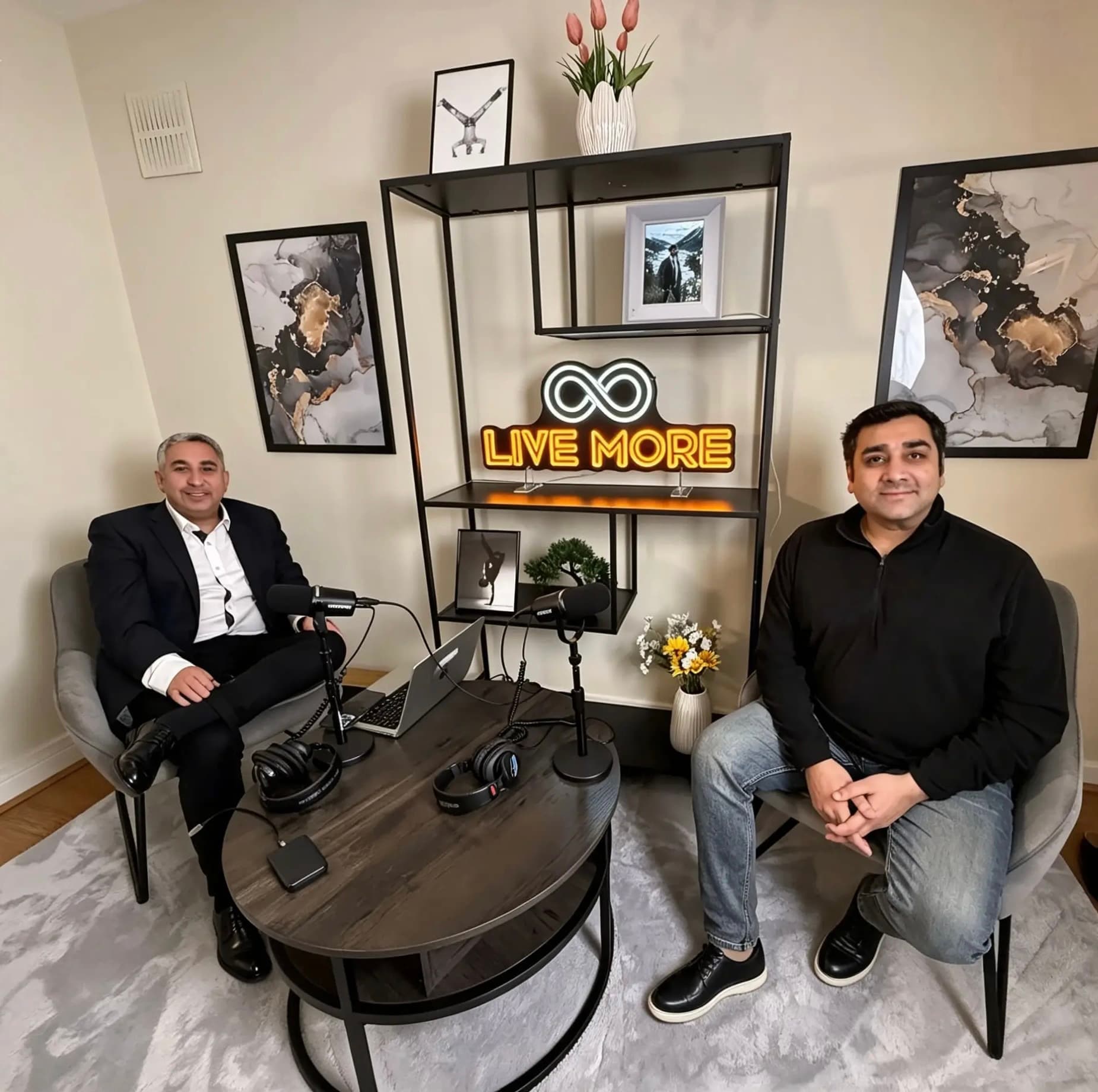Two men sit in a podcast studio with microphones and a "LIVE MORE" neon sign.