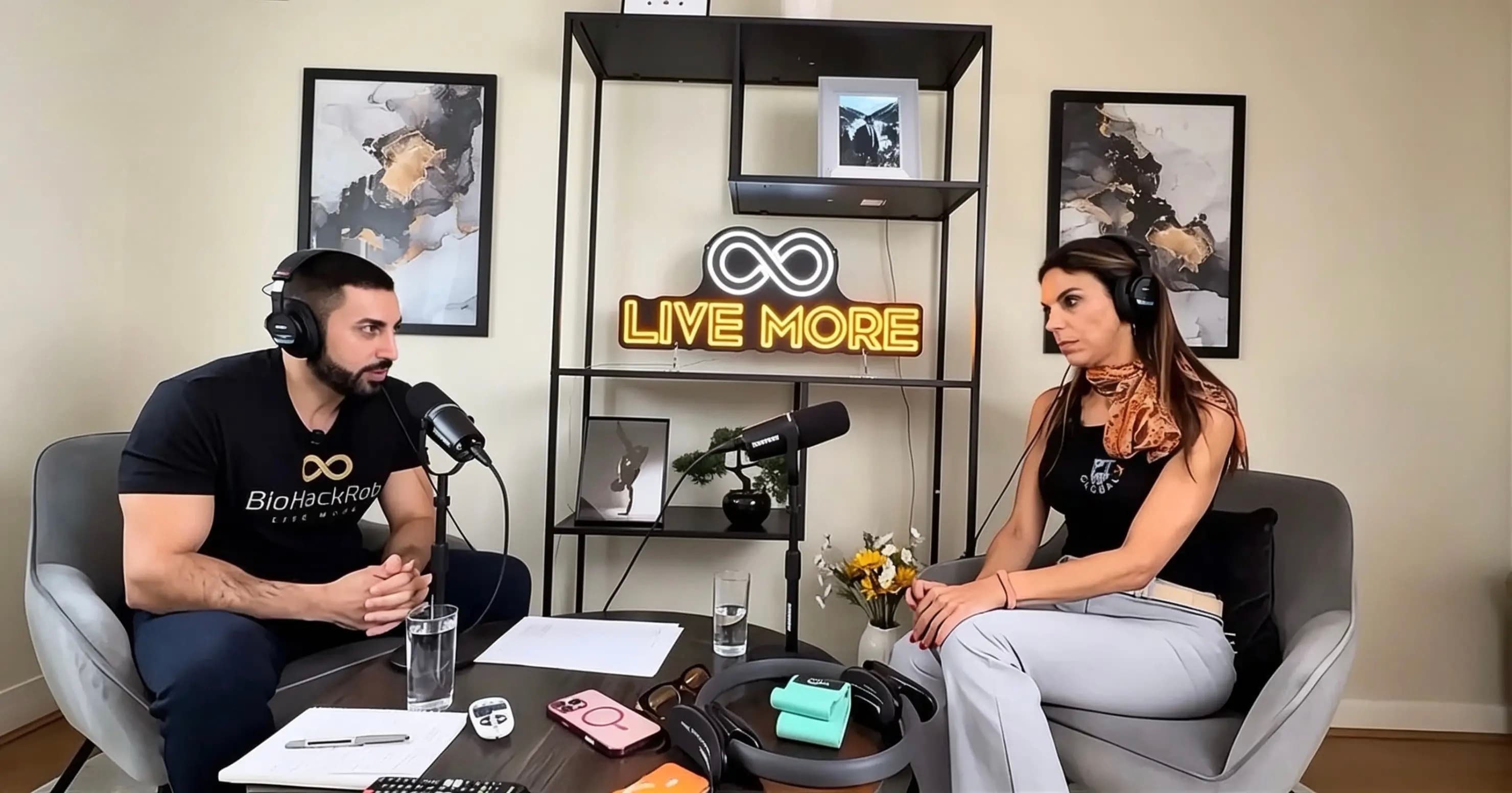 Man and woman recording a podcast in a studio with a Live More neon sign.