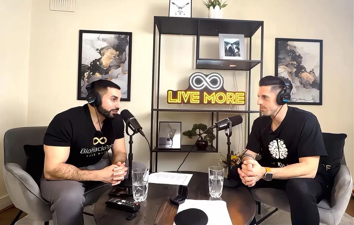 Two men wearing headsets and black shirts recording a podcast in a studio setting.